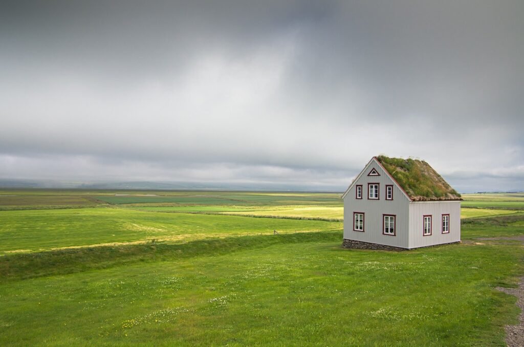 Einsames Haus auf grüne Wiese unter dunklem Himmel