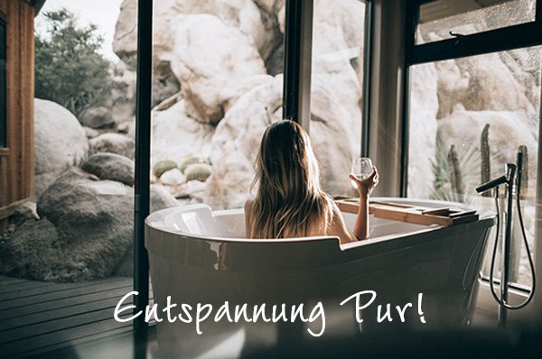 Frau in Badewanne mit Weinglas und schönem Ausblick duch Glaswand