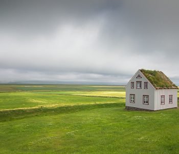 Einsames Haus auf grüne Wiese unter dunklem Himmel